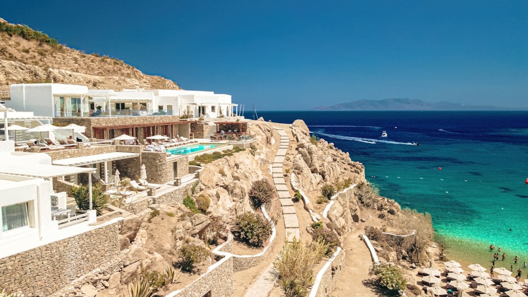 White resort terraced into arid hillside above turquoise sea.